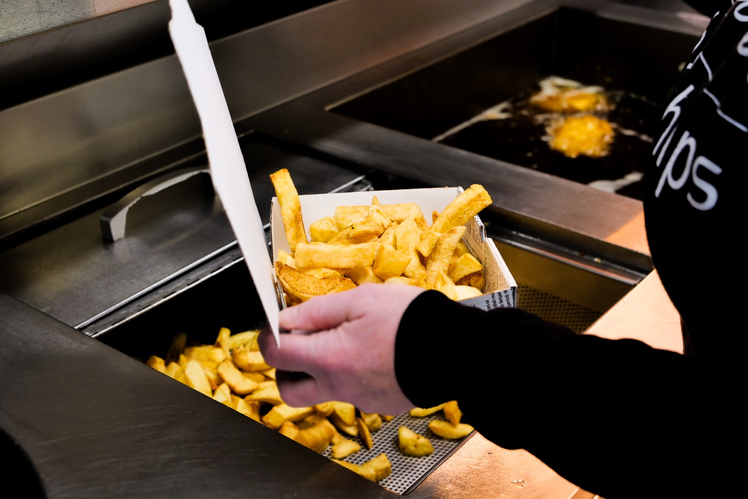 Chips being served into a takeaway box