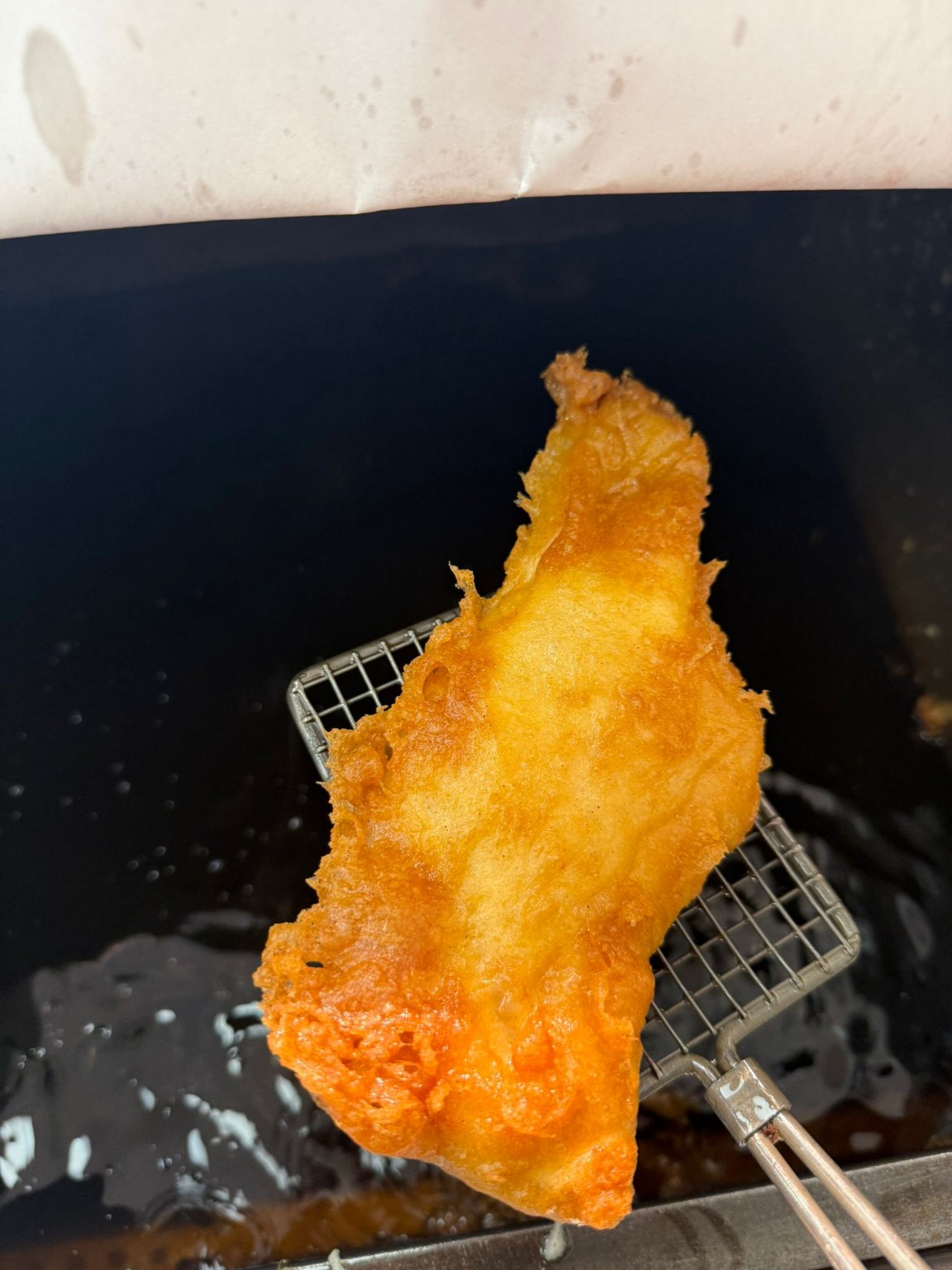 Fresh battered fish being lifted from the fryer